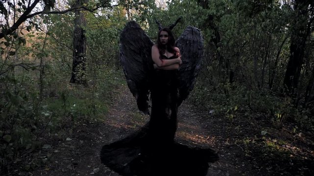 Young maleficent brunette girl standing in the forest
