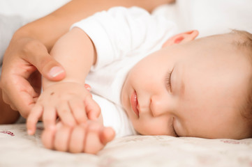 Obraz na płótnie Canvas Little boy lies near his mom resting on the bed.
