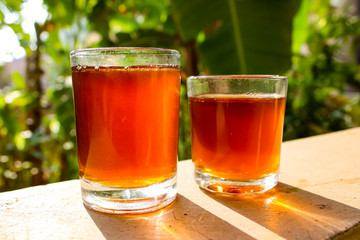 Outdoor Tea pouring into glass cup transparent with day sunlight.
