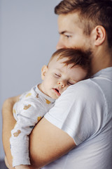 Close up of adorable little boy sleeping deeply and dreaming while his caring father holding him.