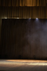 Theater stage with puffs of smoke, illuminated by stage light.