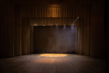 Theater stage with puffs of smoke, illuminated by stage light.