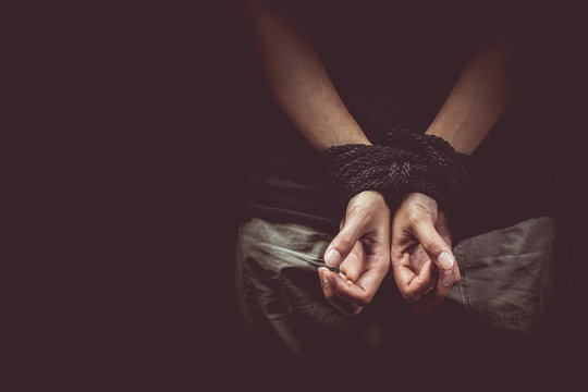 Close-up Of Man Hand Tied With Rope Against Black Background