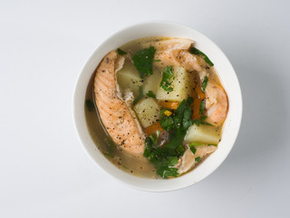 Fish soup in a white bowl. Salmon with potatoes and herbs. Top view