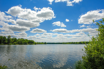 Obraz na płótnie Canvas The blue sky with the clouds above the clear blue lake