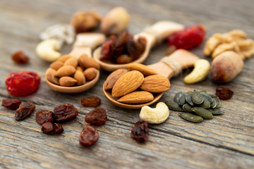 Almonds, apricot seed on a wooden spoons. Raisins, cashews, figs, nuts on top of a wooden board.