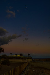 landscape after sunset with a navy blue sky and white moon on the Spanish island of Gran Canari in the Maspalomas dunes