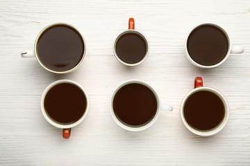 Cups of coffee on white wooden background