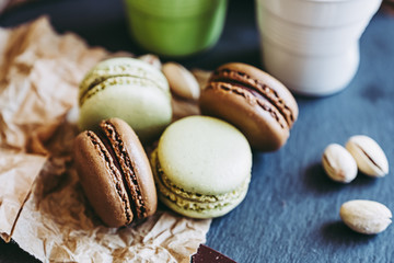 Macarons au chocolat et à la pistache sur une planche ardoise