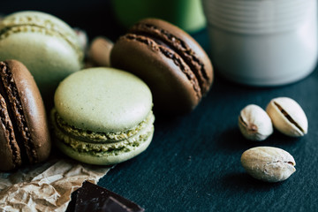 Macarons au chocolat et à la pistache sur une planche ardoise