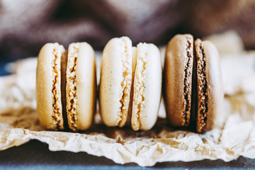 Trois macarons au gout vanille chocolat café sur un fond naturel