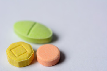 Multicolor tablet pills on gray background.