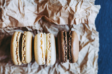 Trois macarons au gout vanille chocolat café sur un fond naturel