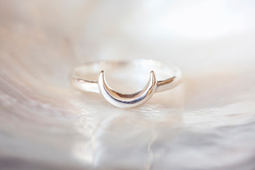 Sterling silver elegant ring in the shape of the moon on natural white shell background