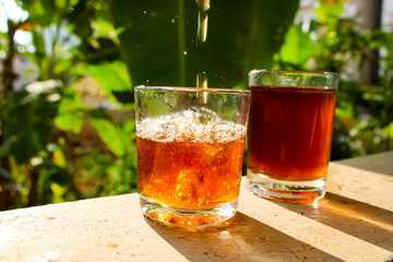 Outdoor Tea pouring into glass cup transparent with day sunlight.

