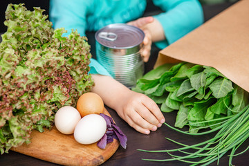 Children's hands collects food in a paper bag. Stock of food for the duration of the coronavirus quarantine. 