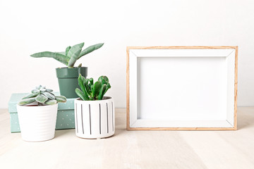 Poster frame mockup, front view, with decor elements, house plants, flowers and blank copy space over the white wall