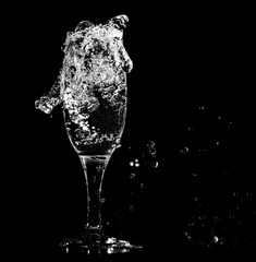Splashes and drops of water in a glass are isolated on a black .