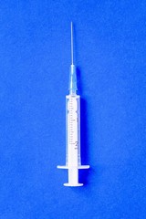 Blank clean injection syringe on blue background. One medical tool. Health care, medicine, medical research, immunization and protection of the population from epidemic or pandemic.