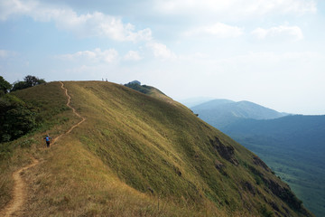 Natural landscape of grassy pathway to the mountain peak with cloudy blue sky