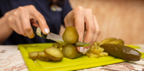 The girl cuts pickles with a knife