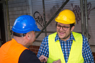 Two civil engineers talking and laughing during work break. Outdoors