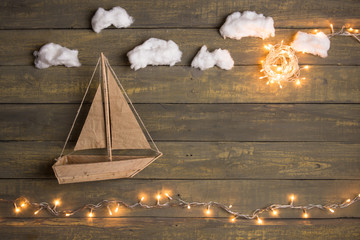 Travel and adventure creative concept - toy boat on a wooden background with cotton clouds....