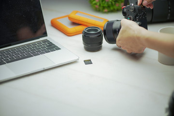 Fototapeta na wymiar hands release the camera lens inmodern interior design coworking space, work desk with laptop and professional camera
