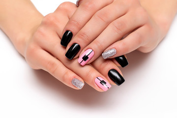 Obraz na płótnie Canvas Black, pink, silver manicure on short square nails with the design of squares and stripes on nameless nails closeup on a white background