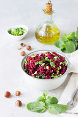Warm buckwheat, beetroot, nuts and herbs salad, light grey concrete background. Vegetarian and vegan food. Healthy food concept. 