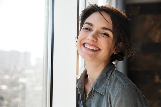 Image of beautiful young joyful woman smiling and looking at camera