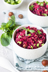 White ceramic bowls with buckwheat, beetroot, nuts and herbs warm salad, light grey concrete background. Dietary balanced food concept. Vegetarian and vegan meal. 