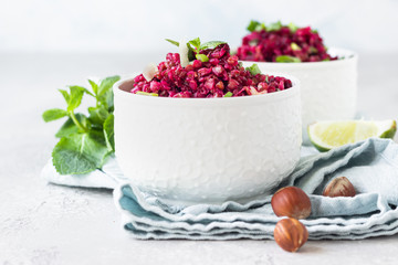White ceramic bowls with buckwheat, beetroot, nuts and herbs warm salad, light grey concrete background. Dietary balanced food concept. Vegetarian and vegan meal. 