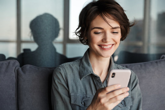 Image of nice young happy woman using mobile phone and smiling