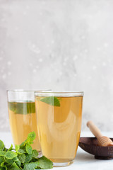 Fresh hot peppermint herbal tea in glasses with fresh mint leaves and honey on light blue stone background. Moroccan tea with mint. 