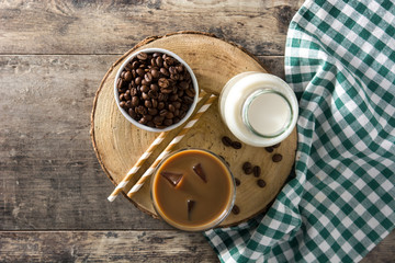 Iced coffee or caffe latte in tall glass on wooden table. Top view