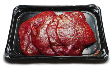 Fresh thin sliced steak marinated in plastic packaging without label, Retail product. White background.