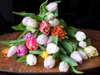 multi-colored tulips are loose on a wooden table