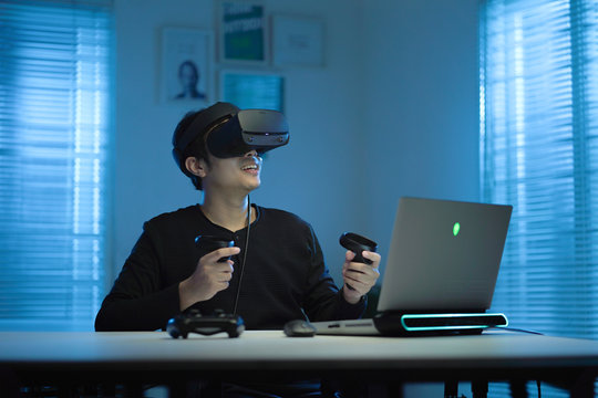 Young Asian man wearing virtual reality glasses in modern interior design coworking studio