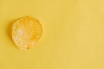 Potato chip on a yellow background. Top view. Copy, empty space for text