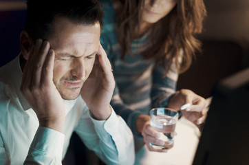 Man having an headache and wife taking care of him