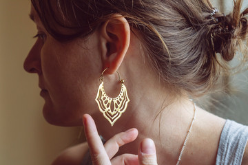 Woman wearing brass earrings in the shape of oriental lotus