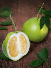 Pomelo fruit with leaves on the old wooden table. Whole pomelo with slice on wooden Background