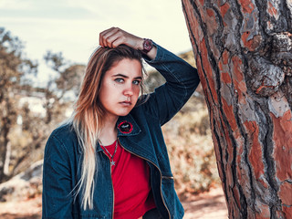 pretty young woman looking at the camera in a blue sweater hatched in a tree in spring