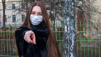 Medical masked woman shows hand direction. Protective coronavirus concept.