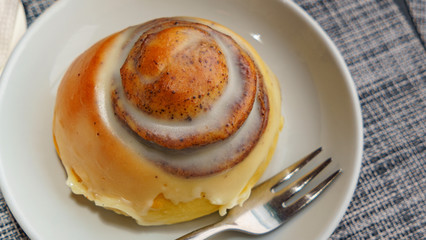 Close-up top view of cinnamon bun on plate and fork. Coffee and dessert concept. Space for text.