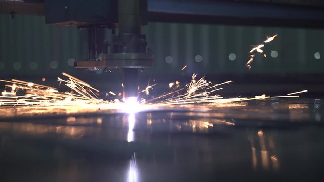 Industrial laser is cutting a pattern on a plywood sheet and moving slowly, close up. 100 fps Slow Motion