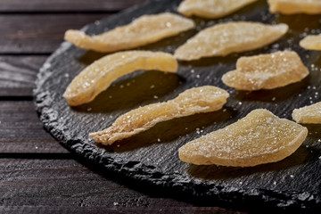 Ginger dried fruit slides spread beautifully on a black plate. side view. on a wooden table. Against viruses and diseases. immune product
