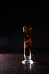alcoholic cocktail on a neutral black background refreshing with coca cola and a slice of lime