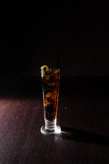 refreshing alcoholic cocktail on a neutral black background with and a slice of lime